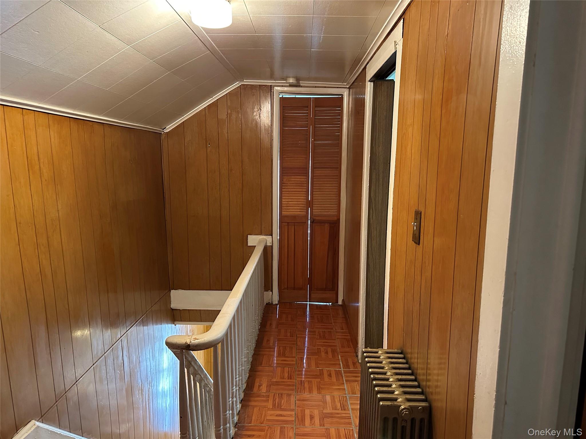 76 Church Street Beacon, NY 12508 - Photo 13 of 26 Corridor with wood walls, lofted ceiling, radiator heating unit, and an upstairs landing