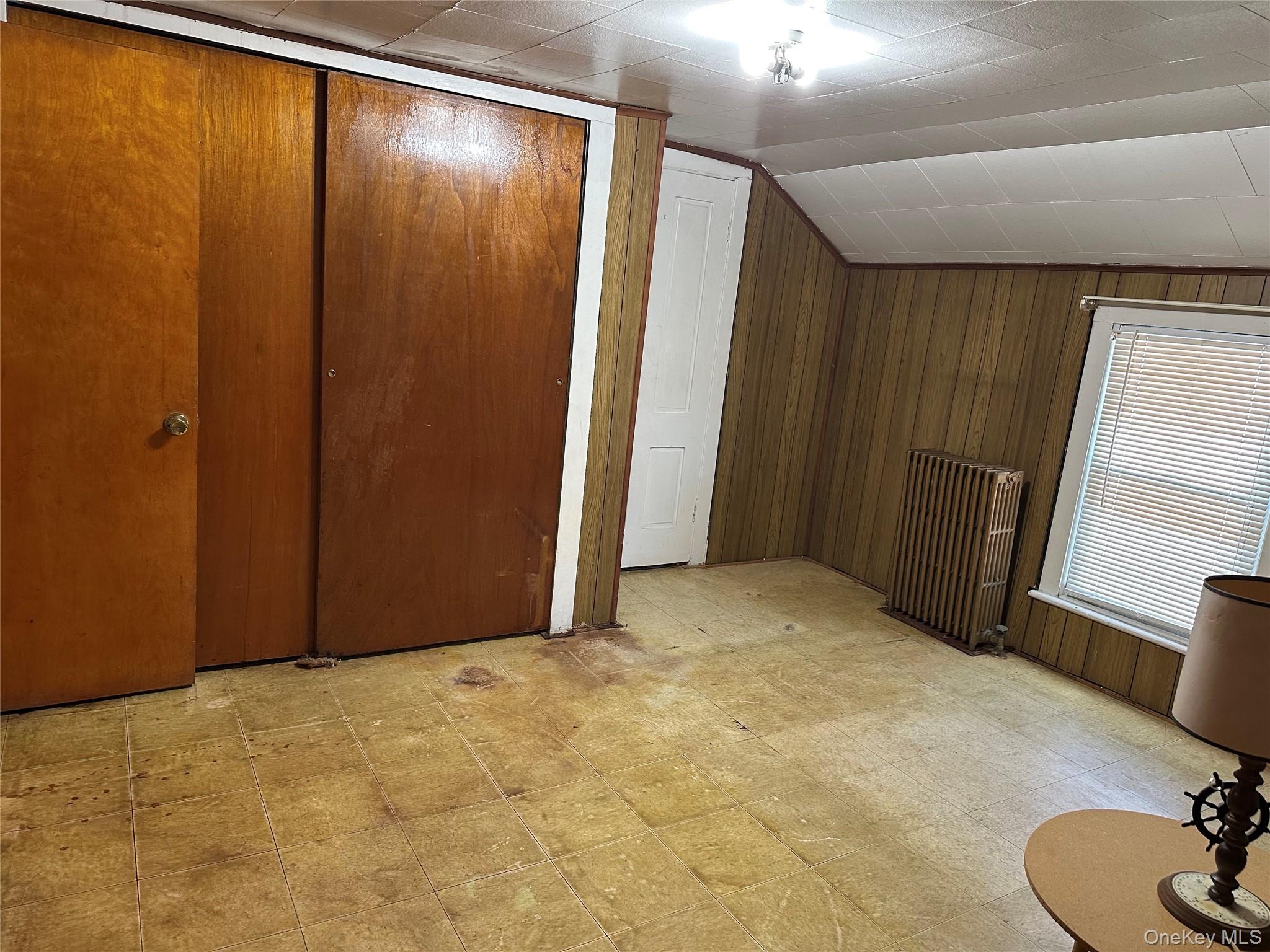 76 Church Street Beacon, NY 12508 - Photo 14 of 26 Bedroom featuring light floors, radiator heating unit, lofted ceiling, and wood walls