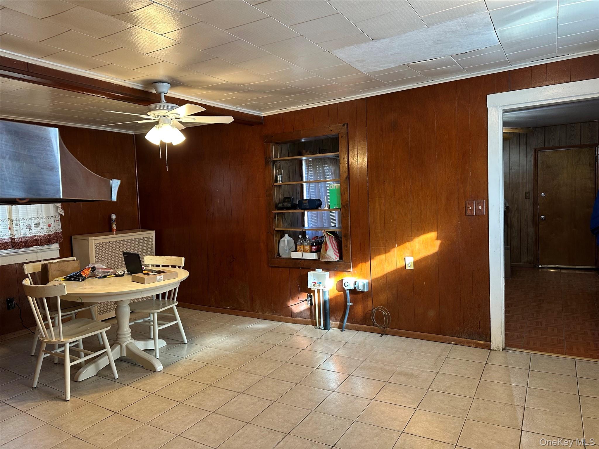 76 Church Street Beacon, NY 12508 - Photo 8 of 26 Dining room with wood walls, a ceiling fan, and light tile patterned floors