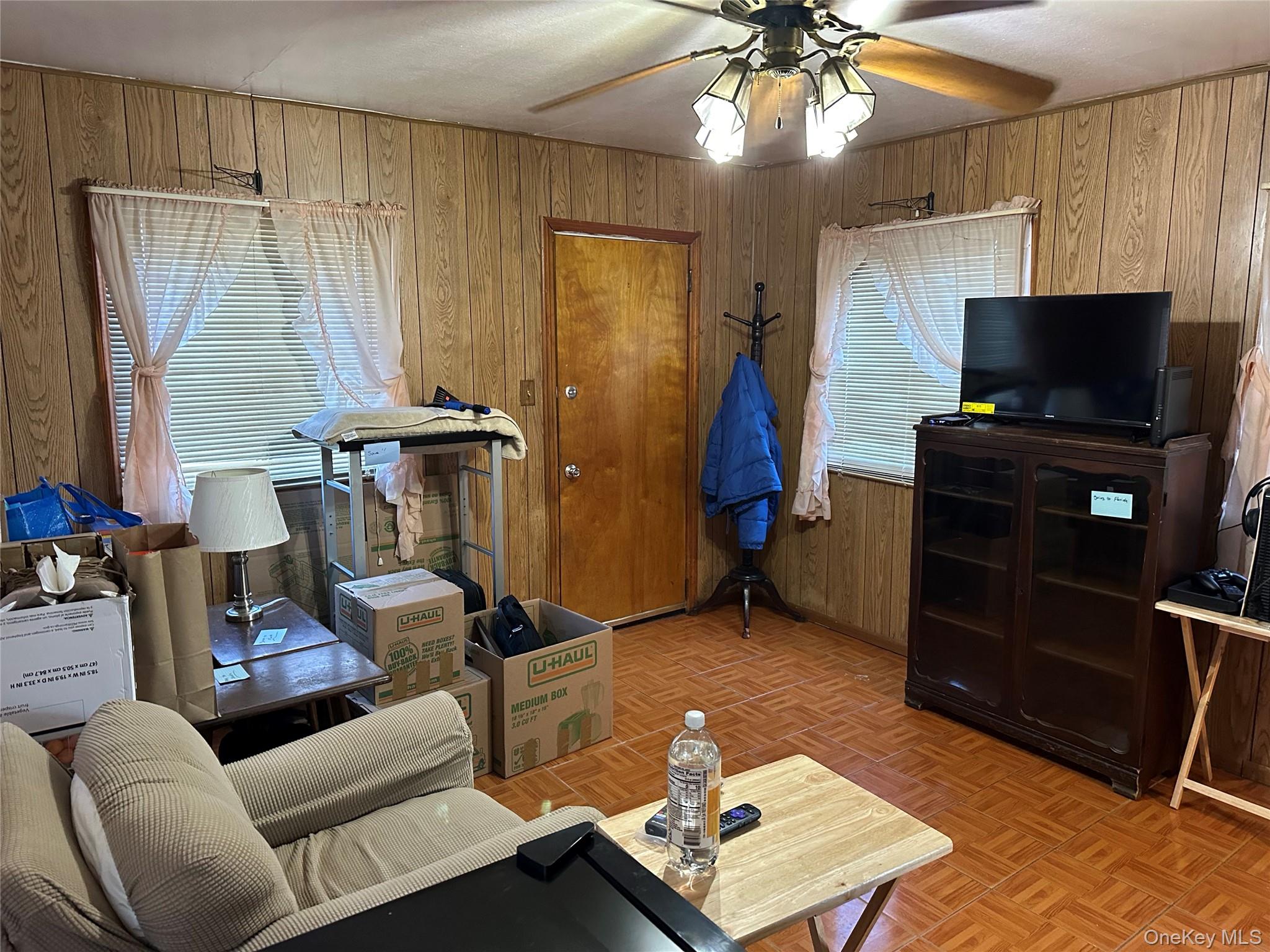76 Church Street Beacon, NY 12508 - Photo 10 of 26 Living area with wood walls and a ceiling fan