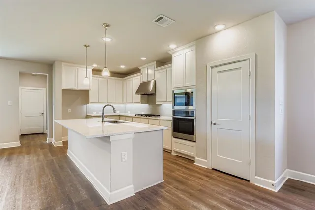 a large kitchen with a large counter top a sink stainless steel appliances and cabinets