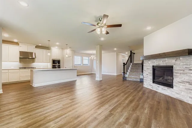 a view of a kitchen and an empty room with wooden floor