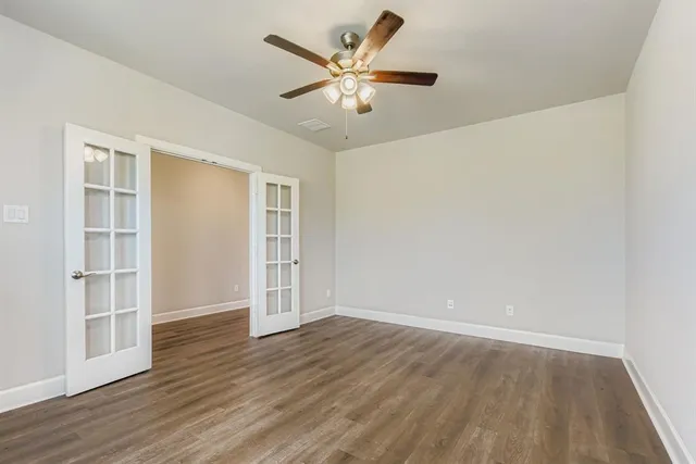 an empty room with wooden floor and windows