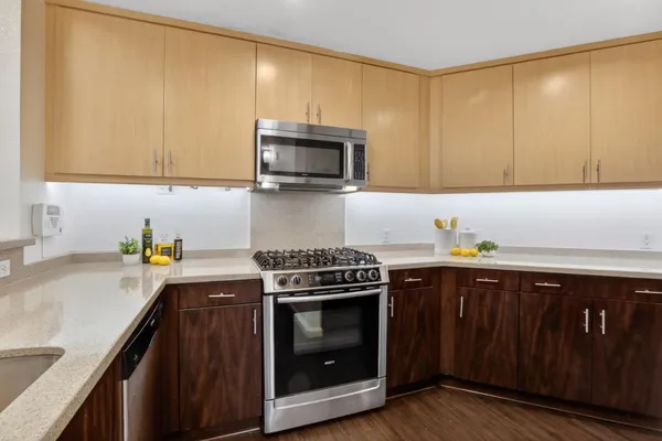 a kitchen with stainless steel appliances a stove a sink cabinets and a wooden floor