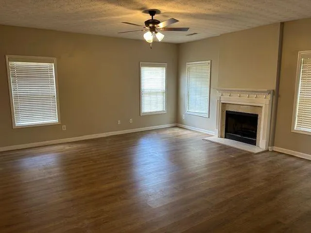 a view of an empty room with wooden floor fireplace and a window