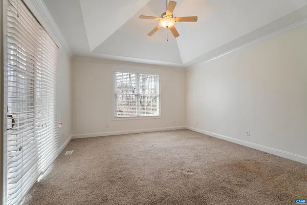 an empty room with windows and chandelier fan