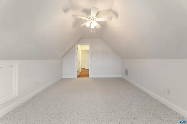 an empty room with a chandelier fan and windows