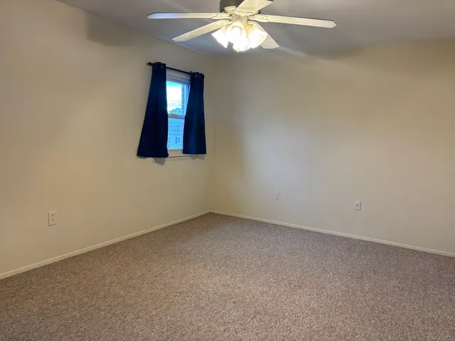 an empty room with a fan and a window