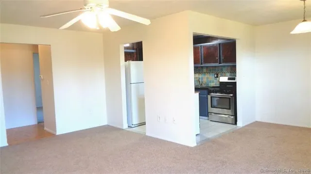 a view of kitchen and empty room with chandelier fan