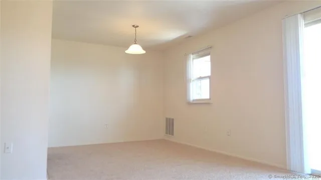 an empty room with a window and hardwood floor