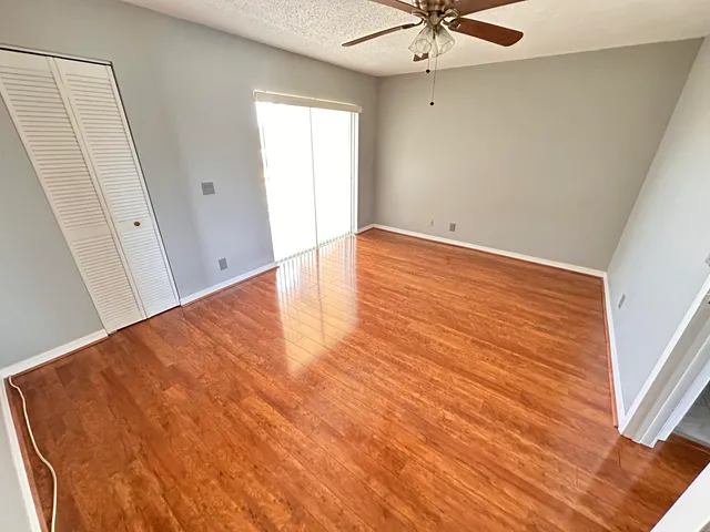 an empty room with wooden floor and ceiling fan
