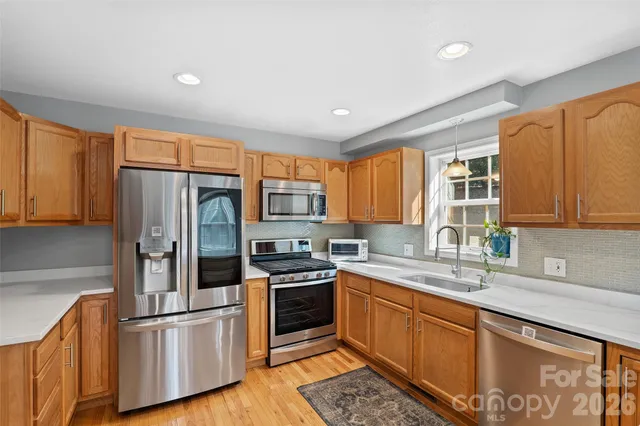 a kitchen with stainless steel appliances granite countertop a refrigerator a sink dishwasher stove and oven