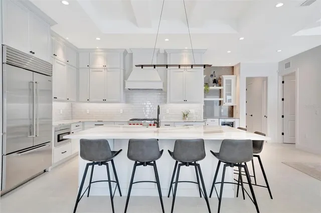 a kitchen with stainless steel appliances granite countertop a sink a stove a refrigerator and chairs