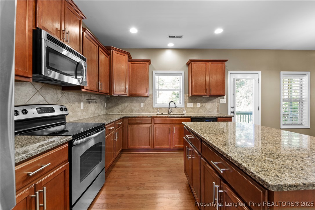 178 Tun Tavern Drive Cameron, NC 28326 - Photo 5 of 30 a kitchen with stainless steel appliances granite countertop wooden cabinets a stove top oven a sink and dishwasher