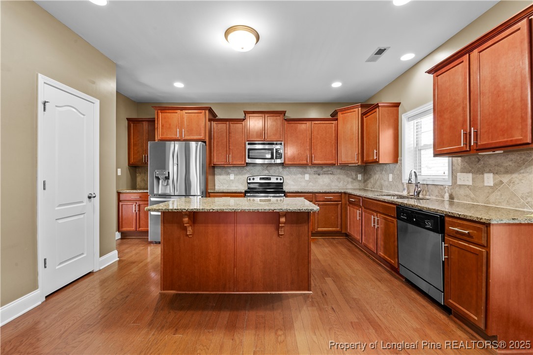 178 Tun Tavern Drive Cameron, NC 28326 - Photo 6 of 30 a kitchen with stainless steel appliances granite countertop wooden cabinets a refrigerator a sink a stove a microwave and wooden floors