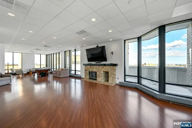 a view of a livingroom with fireplace flat screen tv wooden floor and windows