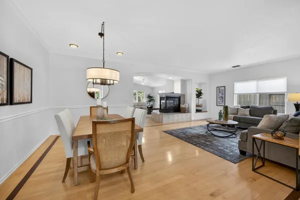 a kitchen with stainless steel appliances granite countertop a stove top oven a sink dishwasher a dining table and chairs with wooden floor