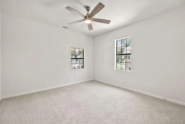 an empty room with windows and fan