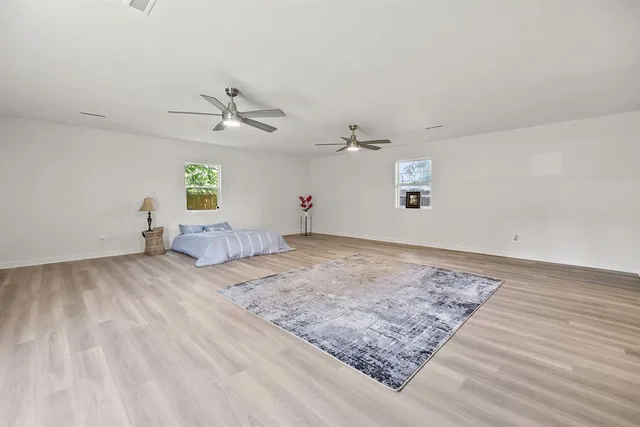 a view of a bedroom with wooden floor and a ceiling fan