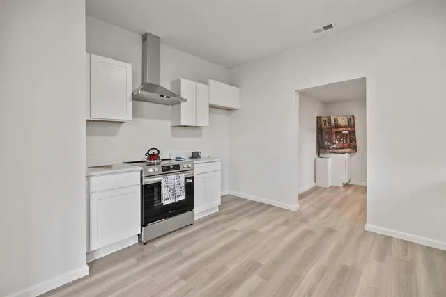 a kitchen with stainless steel appliances white cabinets and wooden floor