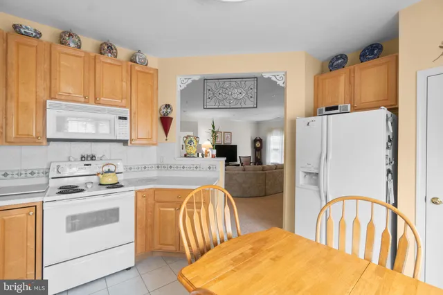 a kitchen with stainless steel appliances granite countertop a refrigerator a stove a sink and white cabinets with wooden floors