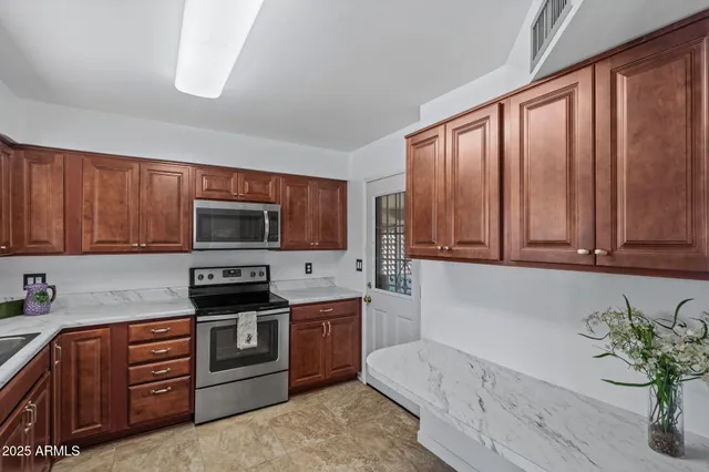 a kitchen with stainless steel appliances granite countertop wooden cabinets a stove top oven a sink and dishwasher