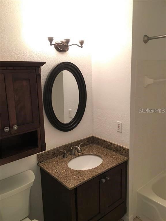 Undisclosed Address Orlando, FL 32819 - Photo 2 of 9 a bathroom with a granite countertop toilet a sink and a mirror