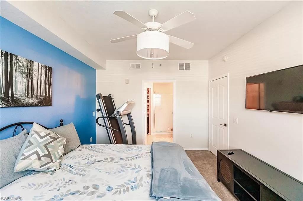 13010 Positano Circle, Unit 101 Naples, FL 34105 - Photo 17 of 29 a bedroom with a bed and a flat tv screen on the dresser