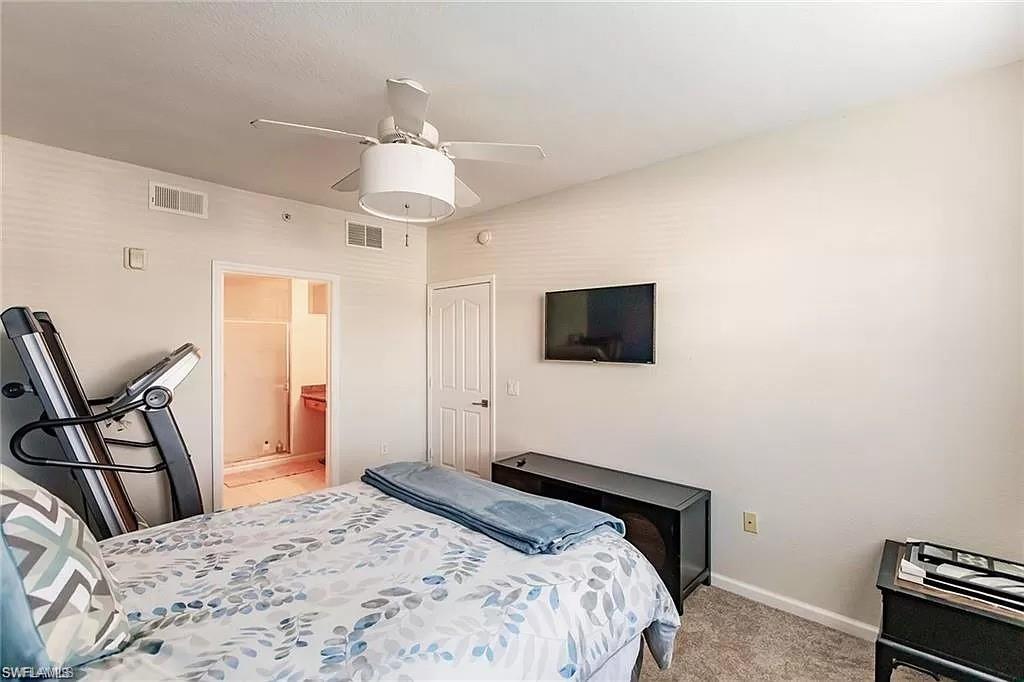 13010 Positano Circle, Unit 101 Naples, FL 34105 - Photo 18 of 29 a bedroom with a bed and a flat screen tv