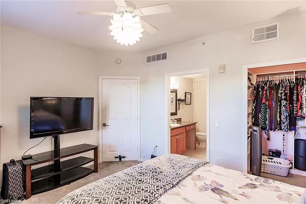 13010 Positano Circle, Unit 101 Naples, FL 34105 - Photo 23 of 29 a bedroom with a bed and a flat screen tv