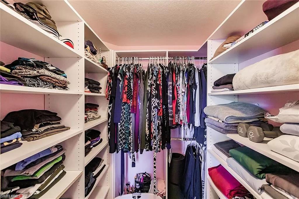 13010 Positano Circle, Unit 101 Naples, FL 34105 - Photo 24 of 29 a view of walk in closet with clothes and shoes