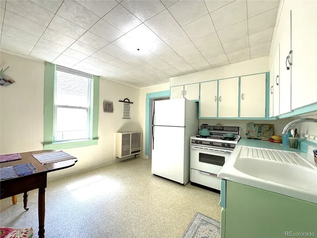 a kitchen with a refrigerator a stove a sink dishwasher with a dining table and chairs with wooden floor