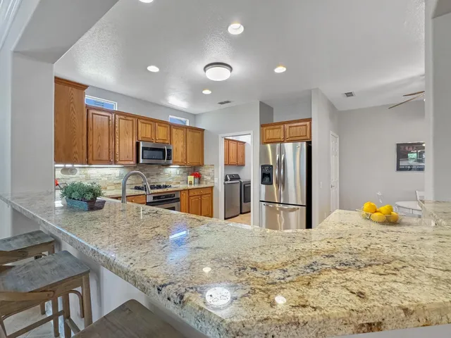 a kitchen with stainless steel appliances granite countertop a sink refrigerator and microwave