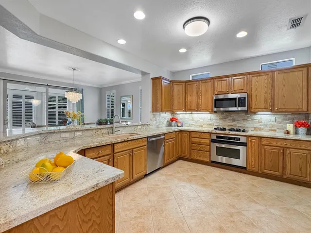 a kitchen with stainless steel appliances granite countertop a sink and stove top oven with wooden floor
