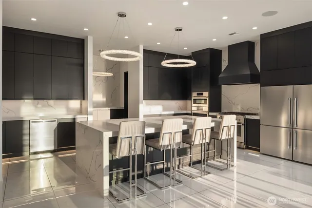 a kitchen with stainless steel appliances kitchen island granite countertop a table chairs and a refrigerator