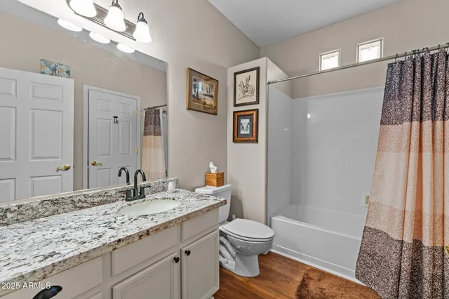 a bathroom with a granite countertop sink a toilet a mirror and shower