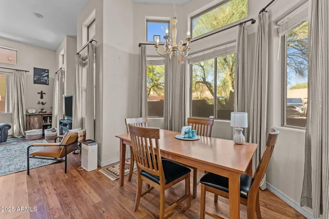 a dining room with wooden floor a chandelier a glass table and chairs