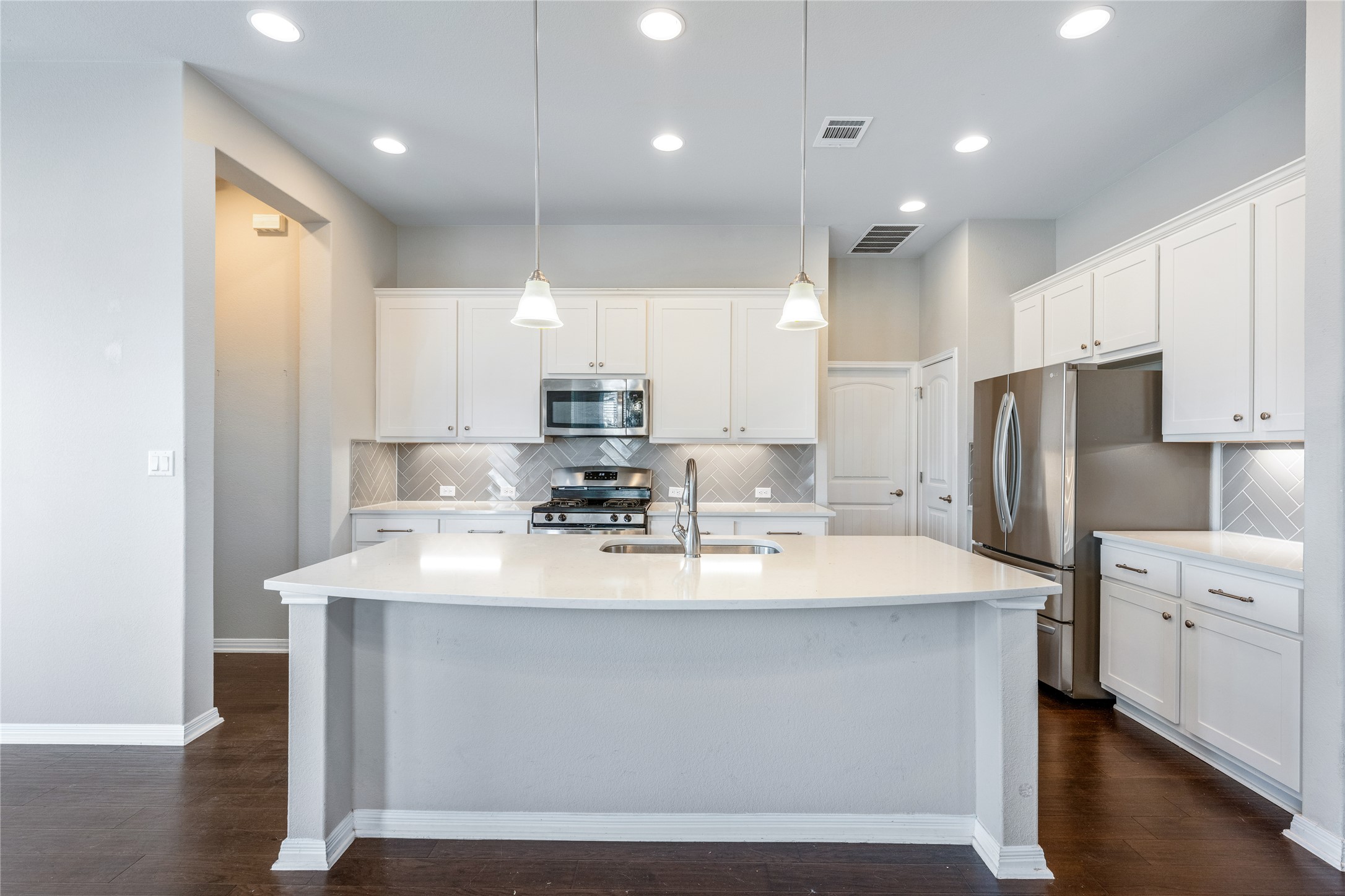 126 Rains Kyle, TX 78640 - Photo 16 of 22 Elegant white cabinetry pairs beautifully with rich hardwood flooring in this open-concept kitchen.