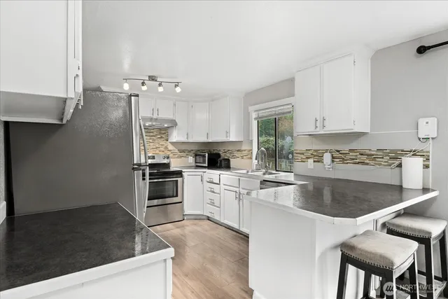 a kitchen with kitchen island granite countertop a sink cabinets and stainless steel appliances