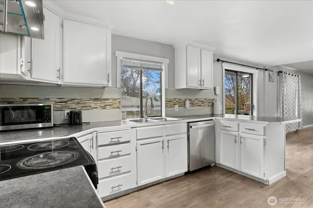 a kitchen with stainless steel appliances granite countertop a stove a sink and white cabinets