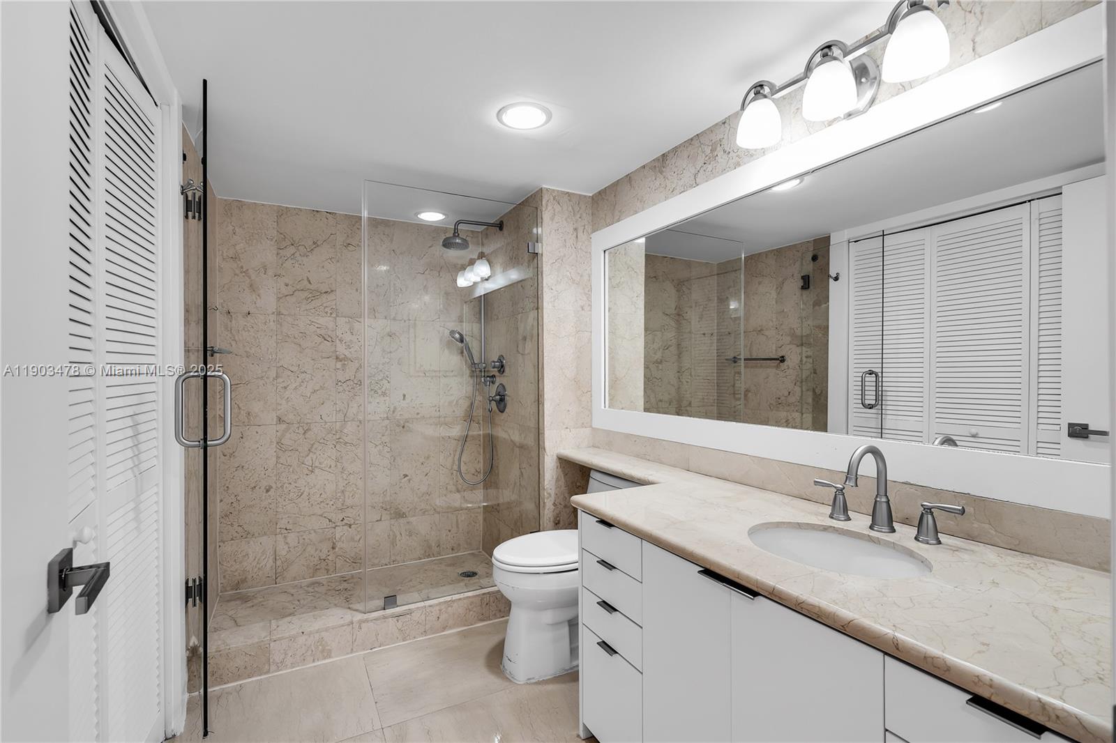 141 Crandon Boulevard, Unit 242 Key Biscayne, FL 33149 - Photo 14 of 42 a bathroom with a granite countertop sink a toilet a mirror and shower