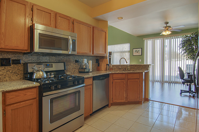 1058 Ripple Ridge, Unit 1058 Darien, IL 60561 - Photo 3 of 13 a kitchen with granite countertop a stove a sink and a microwave