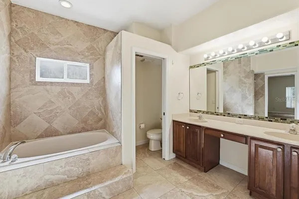 a bathroom with a granite countertop sink mirror bathtub and toilet