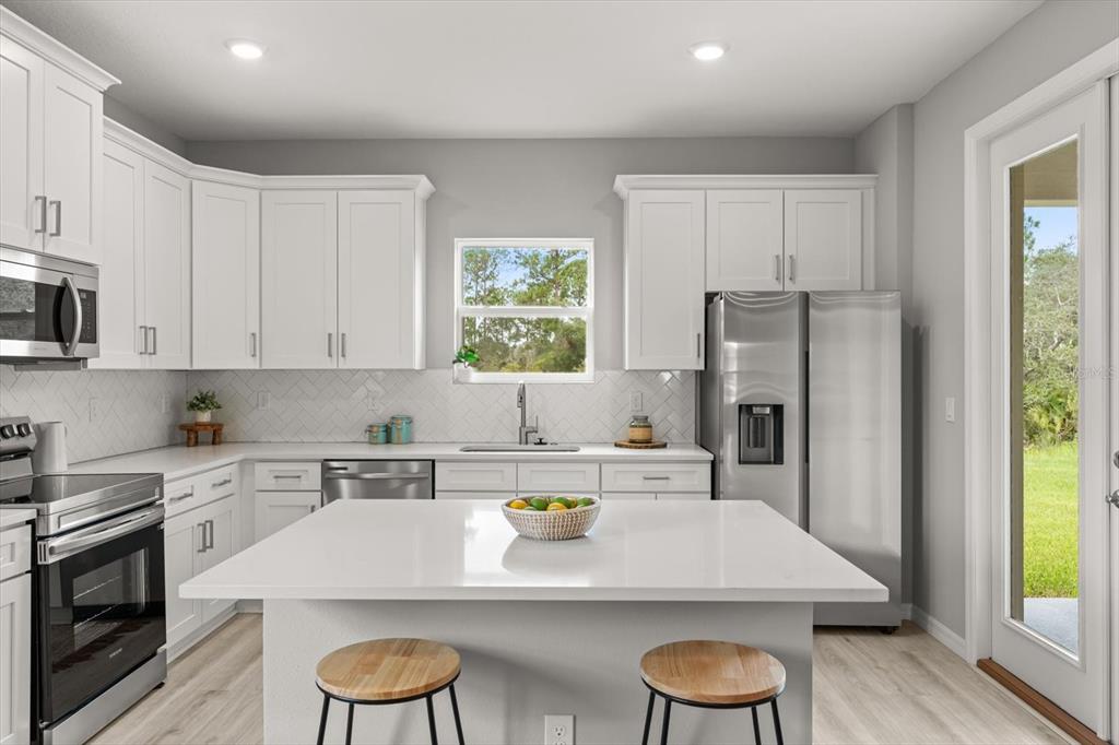 0 Marion Oaks Manor Ocala, FL 34473 - Photo 6 of 24 a kitchen with stainless steel appliances a stove a sink a refrigerator and white cabinets with wooden floor