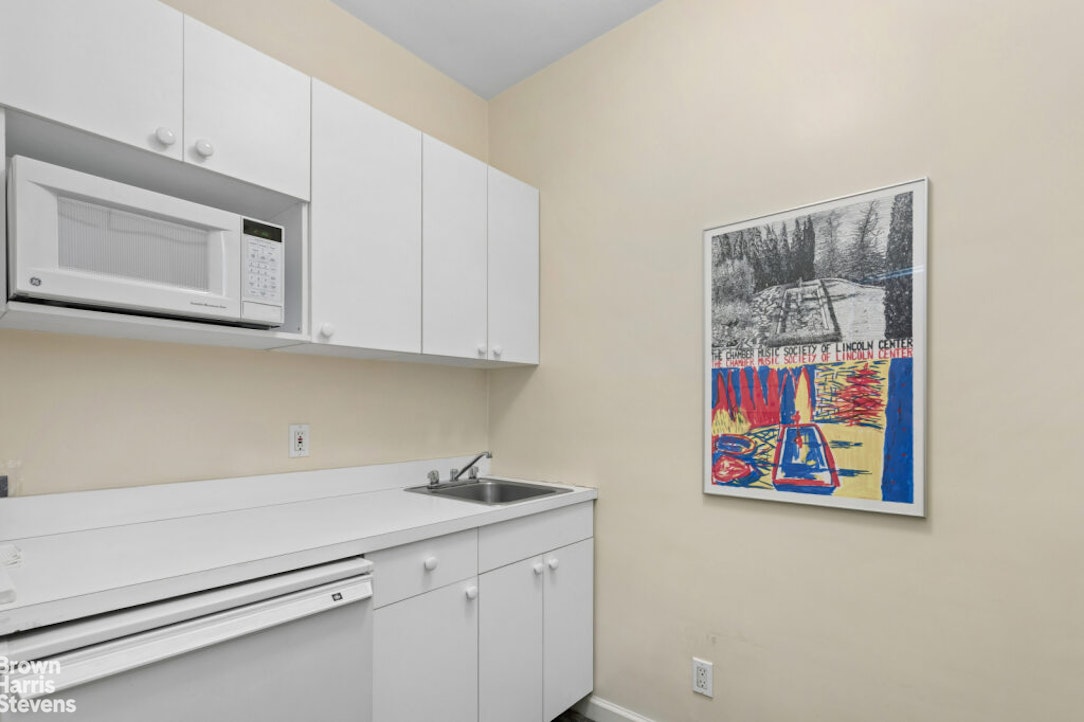 35 East 85th Street, Unit OF3S Manhattan, NY 10028 - Photo 1 of 9 a kitchen with cabinets and a painting on the wall