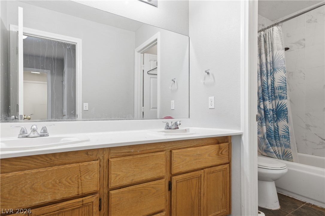 5100 Rancher Avenue Las Vegas, NV 89108 - Photo 22 of 26 Double vanity sinks and a shower with tile surround create a functional and clean bathroom space.