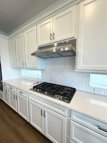 a kitchen with stainless steel appliances granite countertop white cabinets and a stove top oven