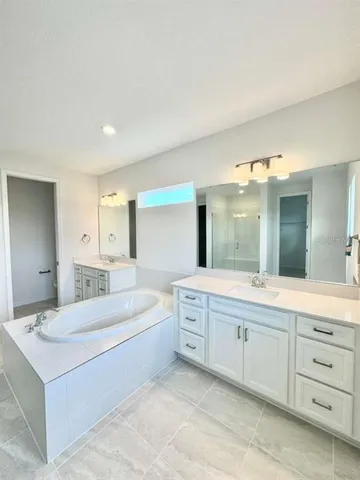 a bathroom with a sink double vanity granite tub and a mirror