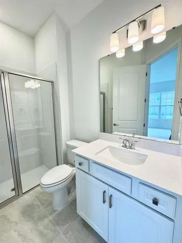 a bathroom with a sink a toilet a mirror and shower