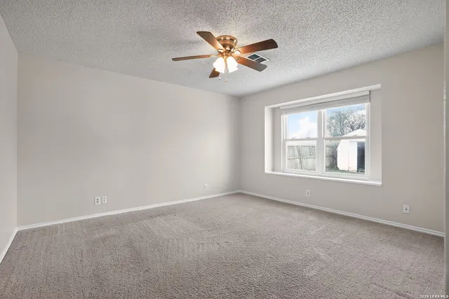 a view of an empty room with window and chandelier fan
